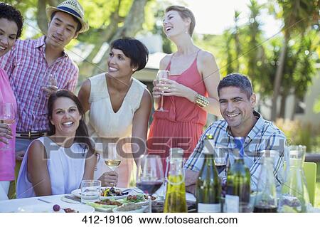 Friends relaxing at table outdoors View Large Photo Image Stock Photograph - Friends relaxing at table outdoors. Fotosearch