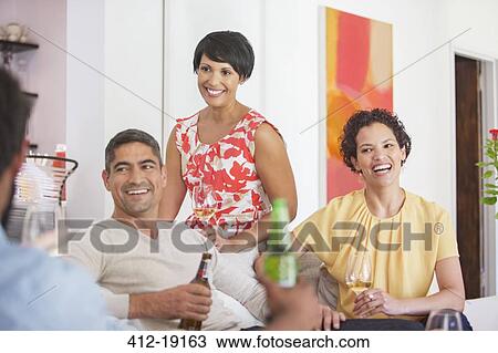 Stock Image - Friends relaxing together at party. Fotosearch