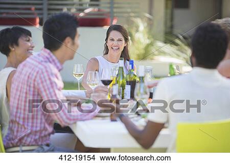 Friends relaxing together at table outdoors View Large Photo Image Picture - Friends relaxing together at table outdoors. Fotosearch