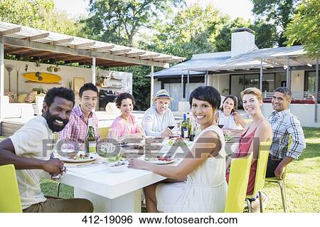 Stock Photograph - Friends smiling at table outdoors. Fotosearch