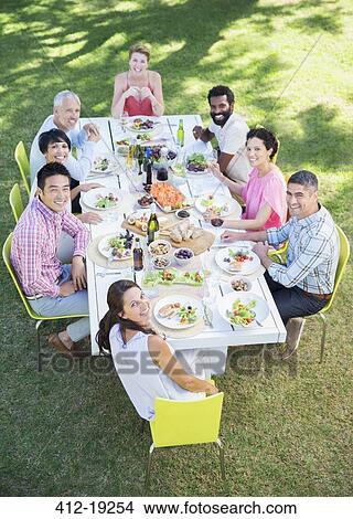 Picture - Friends smiling together at table outdoors. Fotosearch