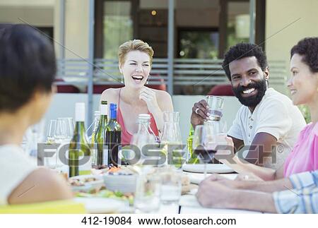 Friends talking at table outdoors View Large Photo Image Picture - Friends talking at table outdoors. Fotosearch