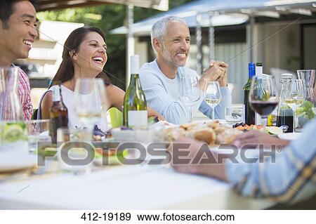 Friends talking at table outdoors View Large Photo Image Stock Photo - Friends talking at table outdoors. Fotosearch