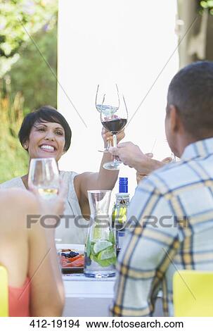 Friends toasting each other at table outdoors View Large Photo Image Picture - Friends toasting each other at table outdoors. Fotosearch