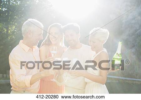 Friends toasting each other with champagne outdoors View Large Photo Image Stock Image - Friends toasting each other with champagne outdoors. Fotosearch