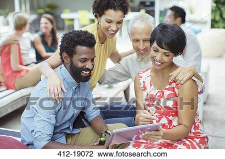 Friends using digital tablet at party View Large Photo Image Stock Image - Friends using digital tablet at party. Fotosearch