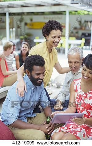 Stock Photo - Friends using digital tablet at party. Fotosearch
