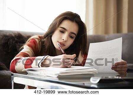 Stock Photo - Girl doing homework at coffee table. Fotosearch