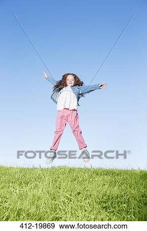 Girl jumping for joy on grassy hill View Large Photo Image Stock Photo - Girl jumping for joy on grassy hill. Fotosearch