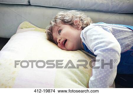 Picture - Girl laying on pillow in living room. Fotosearch