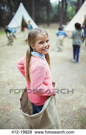 Stock Photo - Girl smiling in sack at campsite. Fotosearch