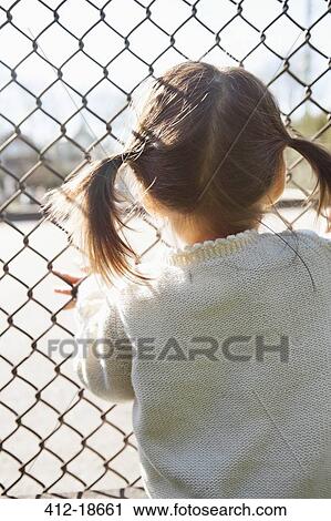 Girl standing at chain link fence View Large Photo Image Stock Image - Girl standing at chain link fence. Fotosearch