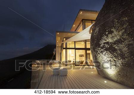 Illuminated modern house with rock feature and balcony View Large Photo Image Picture - Illuminated modern house with rock feature and balcony. Fotosearch