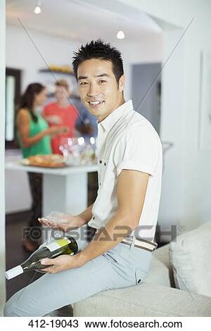 Man holding bottle of wine at party View Large Photo Image Stock Image - Man holding bottle of wine at party. Fotosearch
