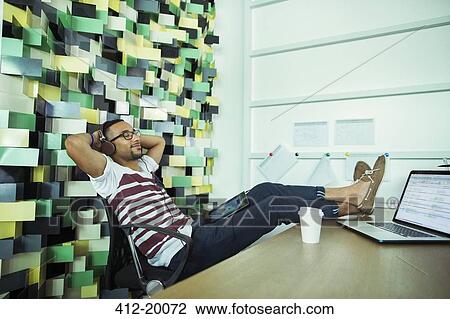 Man relaxing at desk in office View Large Photo Image Stock Image - Man relaxing at desk in office. Fotosearch
