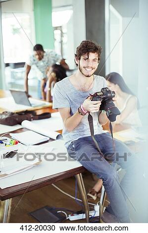 Stock Image - Man reviewing photos in office. Fotosearch