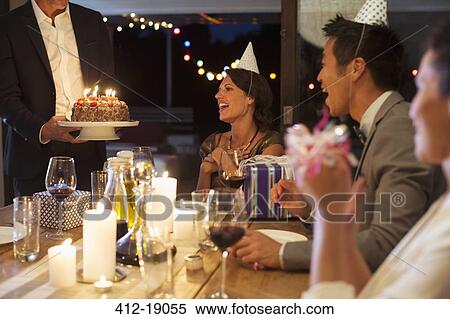 Stock Photography - Man serving birthday cake at party. Fotosearch
