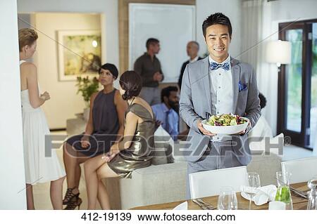 Stock Photo - Man serving food at dinner party. Fotosearch