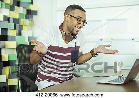 Man shrugging at laptop in office View Large Photo Image Stock Photograph - Man shrugging at laptop in office. Fotosearch