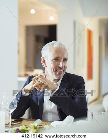 Stock Image - Man sitting at dinner party. Fotosearch