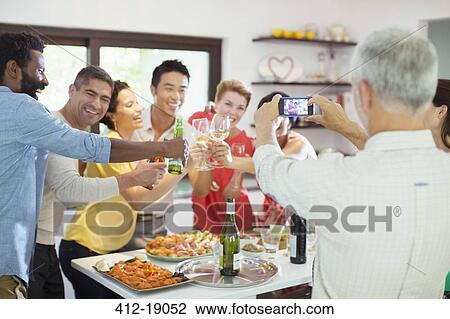 Man taking picture of friends at party View Large Photo Image Stock Image - Man taking picture of friends at party. Fotosearch