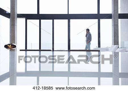 Man talking on cell phone in modern living room View Large Photo Image Stock Photography - Man talking on cell phone in modern living room. Fotosearch