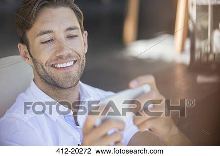 Man using cell phone in armchair View Large Photo Image Stock Image - Man using cell phone in armchair. Fotosearch