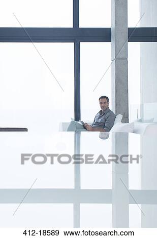 Man using cell phone on sofa in modern house View Large Photo Image Stock Photo - Man using cell phone on sofa in modern house. Fotosearch