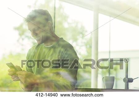 Man using cell phone viewed through window View Large Photo Image Stock Image - Man using cell phone viewed through window. Fotosearch