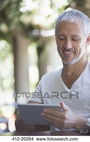 Man using digital tablet at table View Large Photo Image Picture - Man using digital tablet at table. Fotosearch