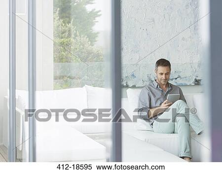 Man using digital tablet on sofa View Large Photo Image Stock Photography - Man using digital tablet on sofa. Fotosearch