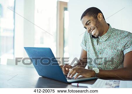Man using laptop at desk in office View Large Photo Image Stock Photography - Man using laptop at desk in office. Fotosearch