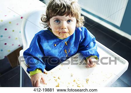 Messy baby girl eating in high chair View Large Photo Image Stock Image - Messy baby girl eating in high chair. Fotosearch