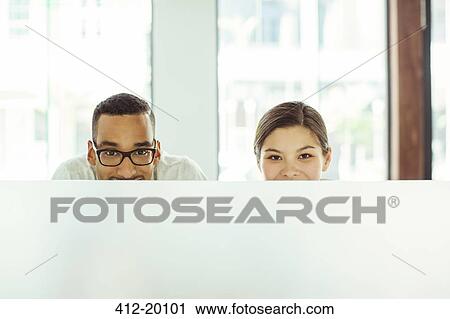Stock Image - People peering over cubicle in office. Fotosearch