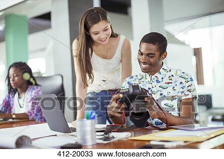 People reviewing photos together in office View Large Photo Image Stock Image - People reviewing photos together in office. Fotosearch