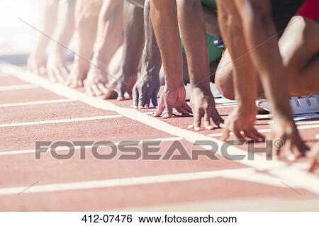 Stock Photograph - Runners poised at starting blocks on track. Fotosearch