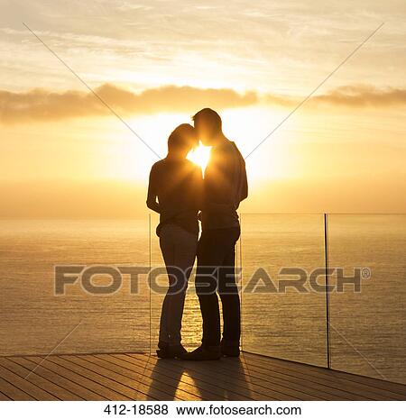 Stock Photo - Silhouette of couple at sunset over ocean. Fotosearch