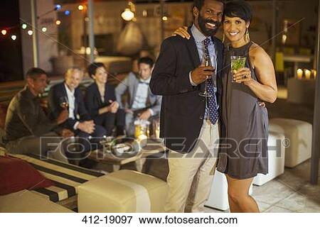 Smiling couple hugging at party View Large Photo Image Stock Photo - Smiling couple hugging at party. Fotosearch