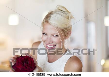 Stock Photo - Smiling woman holding red flower. Fotosearch