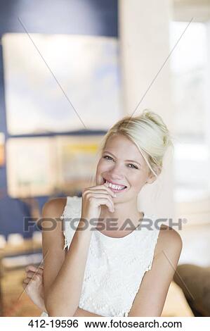 Stock Photograph - Smiling woman standing in living room. Fotosearch
