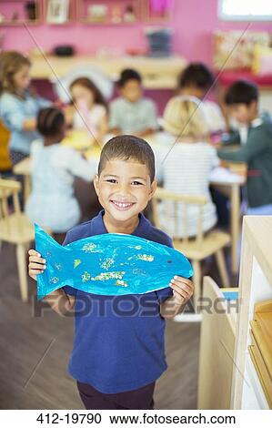 Student holding painted fish in classroom View Large Photo Image Stock Image - Student holding painted fish in classroom. Fotosearch