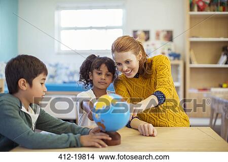 Students and teacher examining globe in classroom View Large Photo Image Picture - Students and teacher examining globe in classroom. Fotosearch