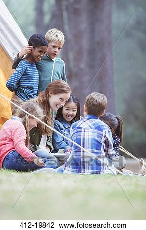 Stock Image - Students and teacher reading at campsite. Fotosearch