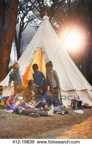 Students and teacher reading at teepee at campsite View Large Photo Image Stock Photo - Students and teacher reading at teepee at campsite. Fotosearch
