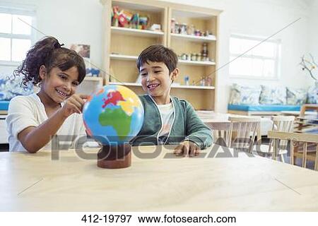 Stock Photo - Students examining globe in classroom. Fotosearch
