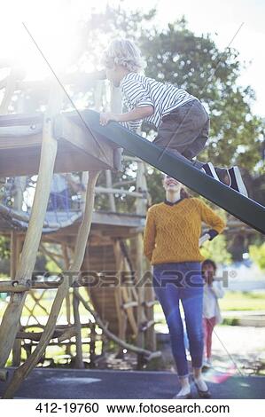 Stock Image - Teacher watching student play on play structure. Fotosearch