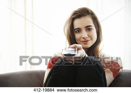 Picture - Teenage girl watching television on sofa. Fotosearch