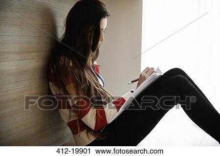 Stock Image - Teenage girl writing in notebook. Fotosearch