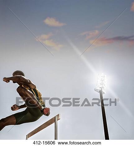 Stock Photograph - Track and field athlete clearing hurdle. Fotosearch