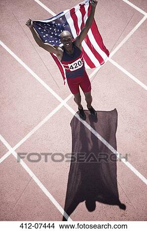 Picture - Track and field athlete holding American flag on track. Fotosearch